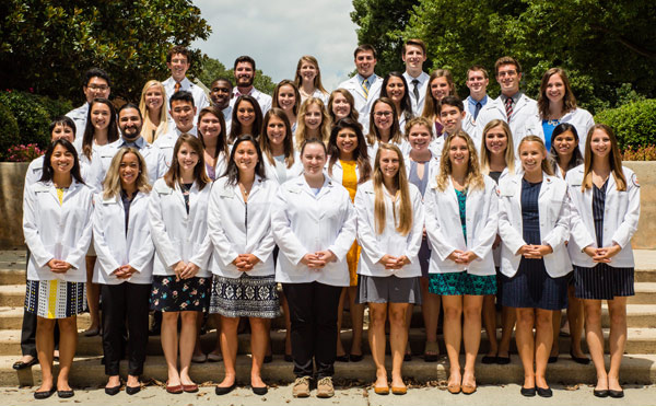 Large group of students with white coats standing on steps