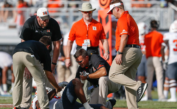 A group of Mercer personnel surround a football player who appears to be injured