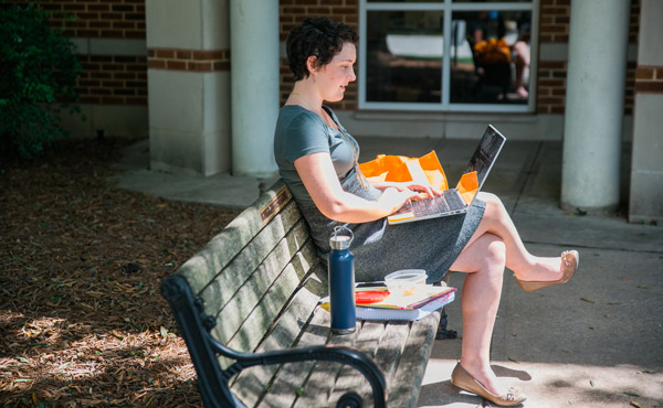 Female student studying on bench.