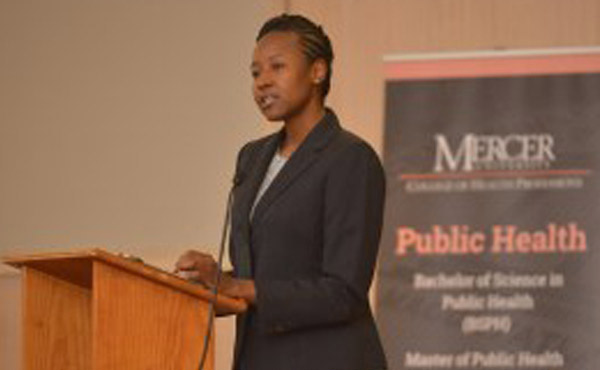 A person behind a lectern with a Mercer Public Health banner in the background